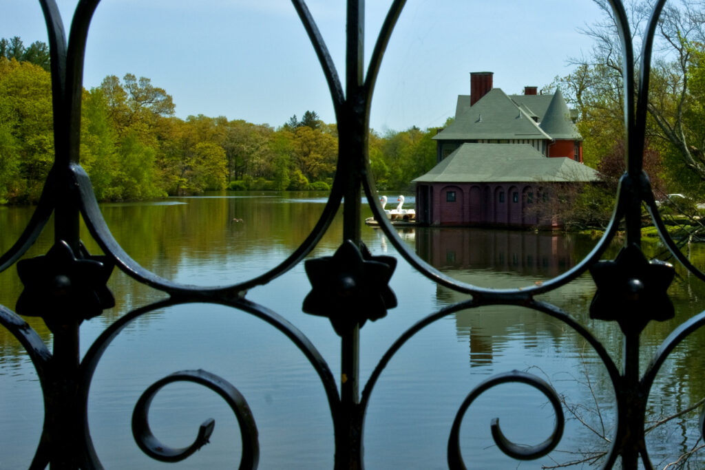 Boathouse and lake through an iron fence